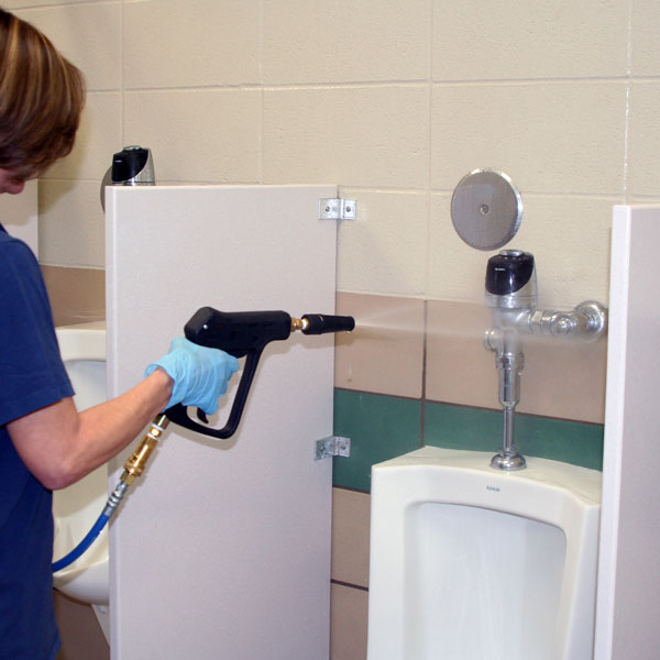 Women cleaning urinal with high pressure spray gun.
