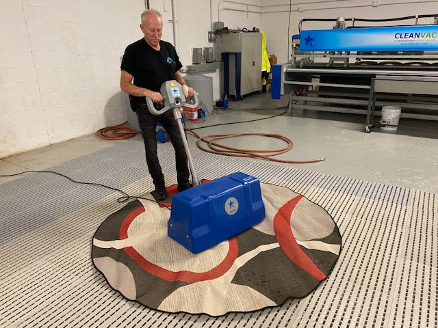 Technician cleaning rug with DryMaster rug duster machine
